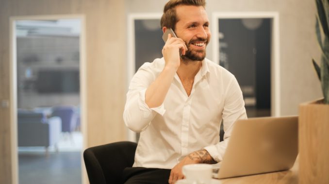 smiling-formal-male-with-laptop-chatting-via-phone-3760263